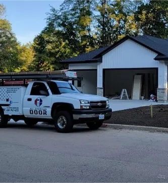 An All American Door company car sits parked in front of a modern residential home.