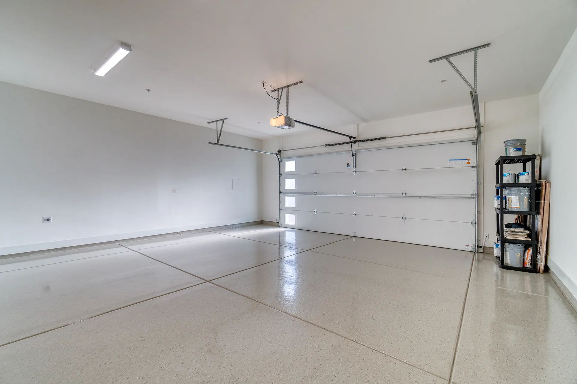 Clean and empty garage interior with polished concrete floors and organized storage shelves on the right.
