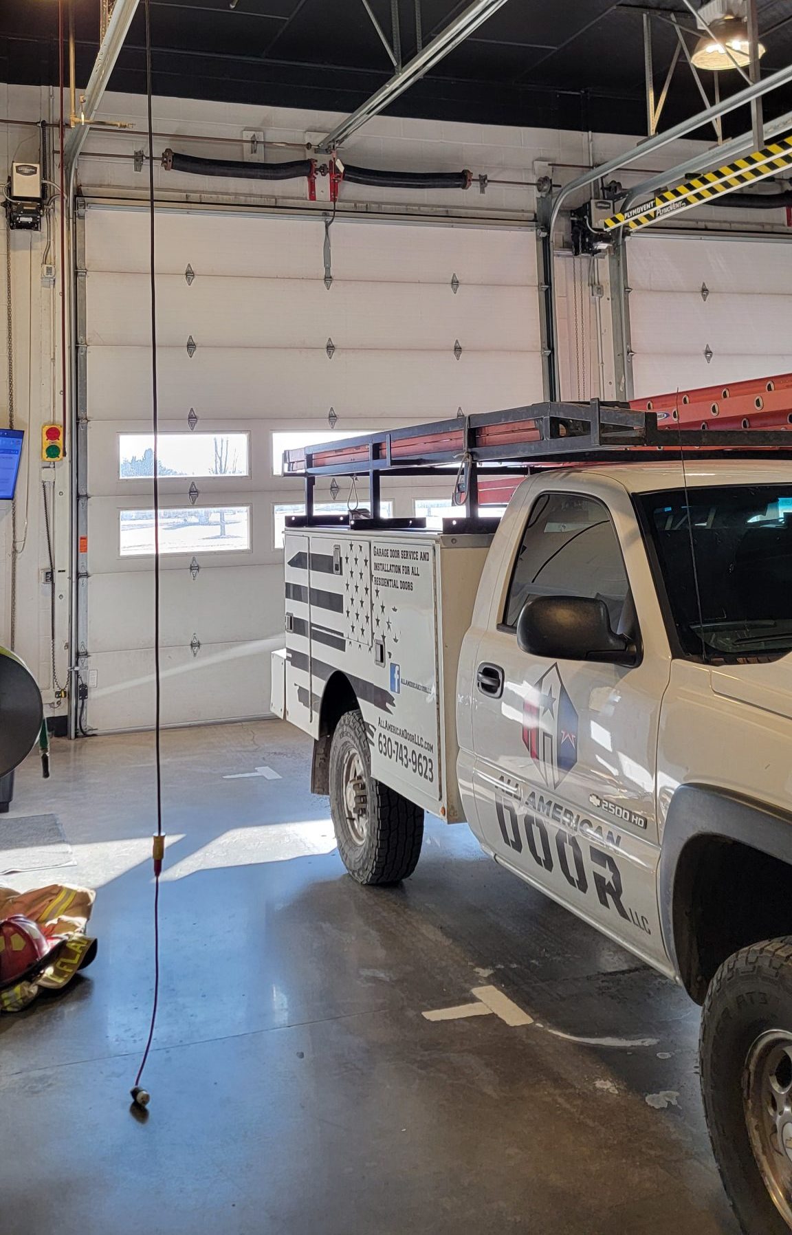 Image of the All American Door Truck parked inside of the Fire house. The background is the garage door