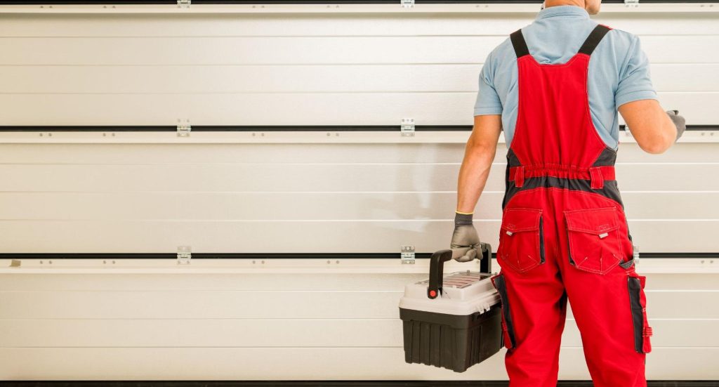 Professional holding a toolbox next to a garage.