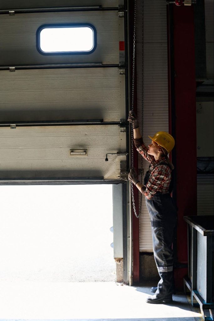 Woman engineer lifting roller garage door for maintenance access