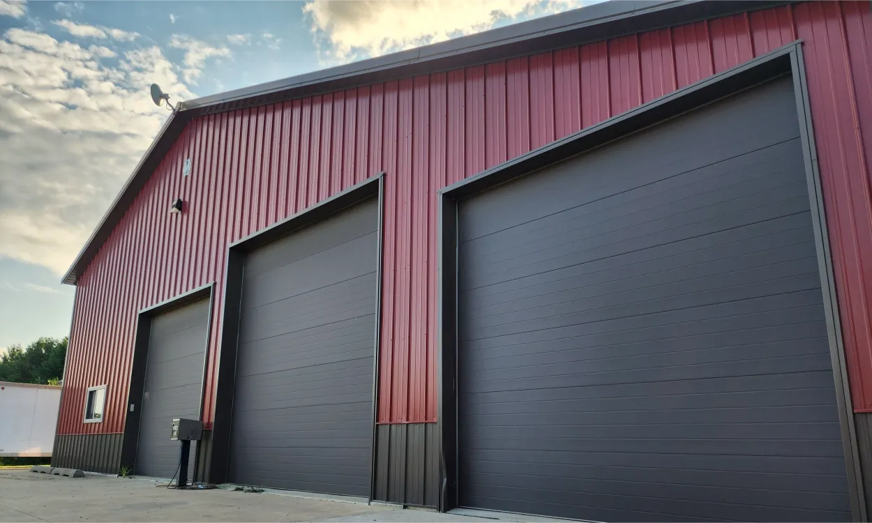 Wide camera shot of a warehouse with three garage doors.